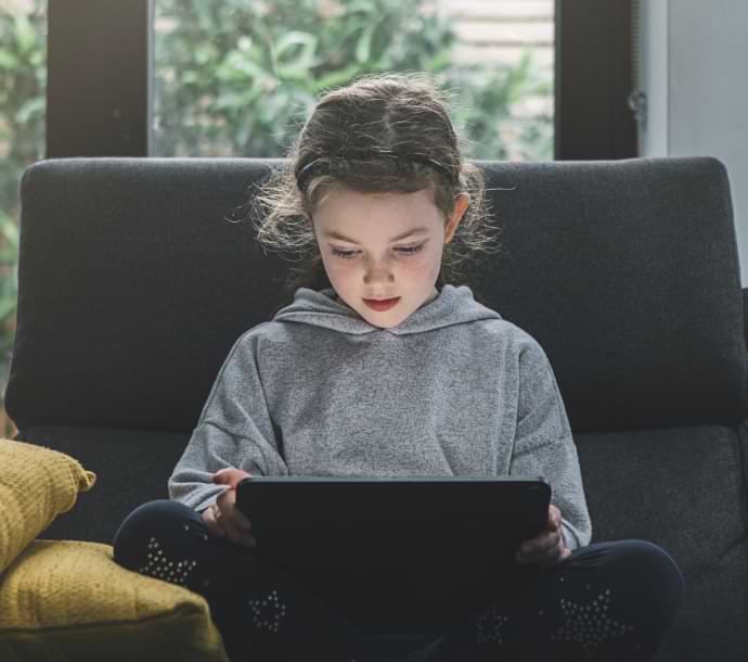 meisje op bank met laptop waarop Norton Family wordt gestart.