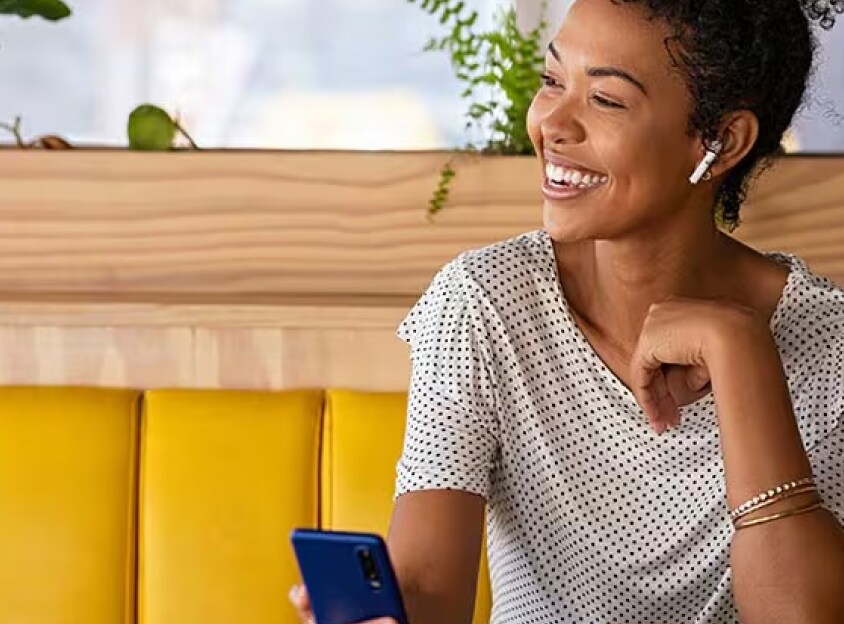 Zittende vrouw die lacht tijdens een telefoongesprek